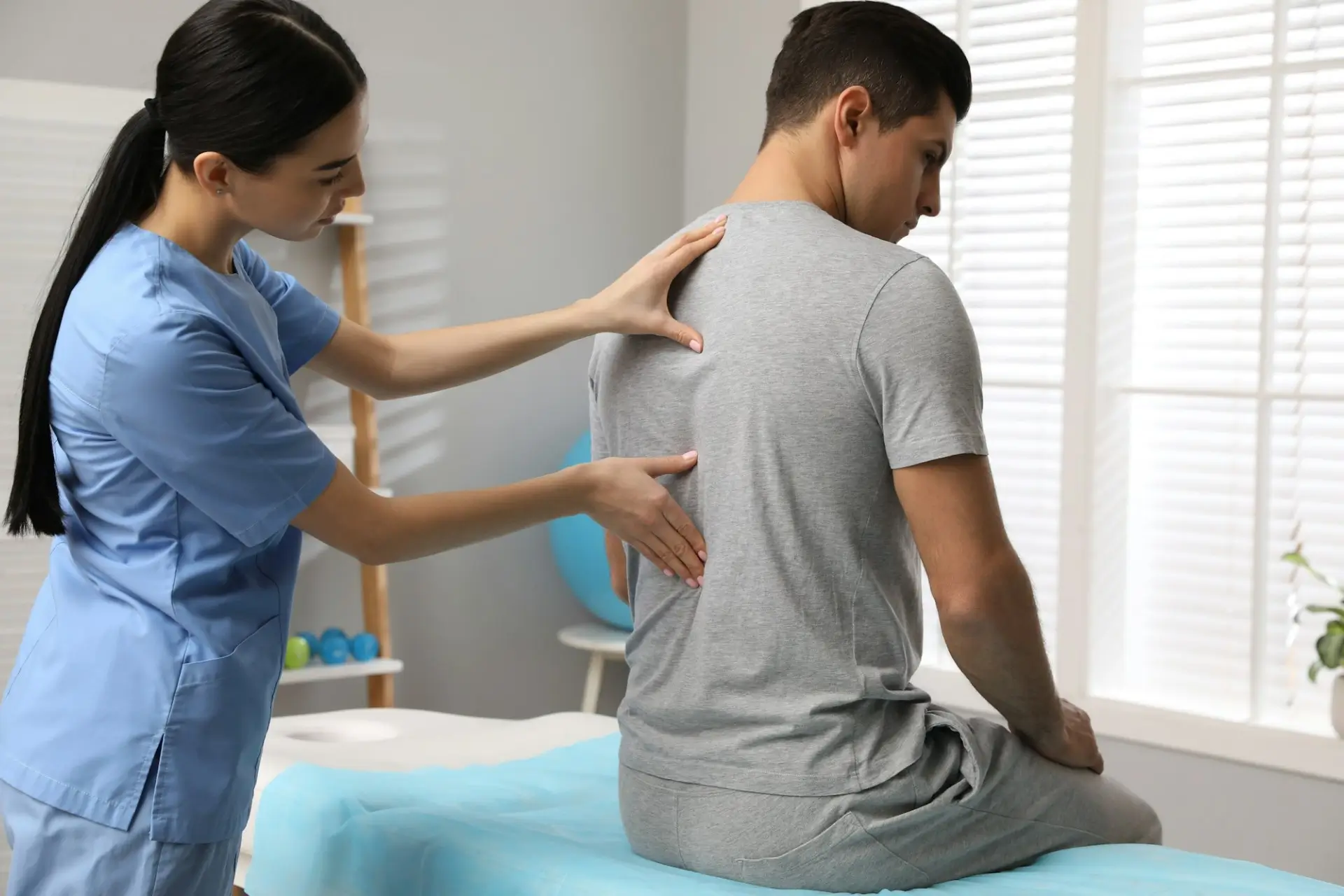 A medical specialist performing a physical back examination on a seated patient to locate the source of spinal discomfort for a back pain treatment plan in Las Vegas.